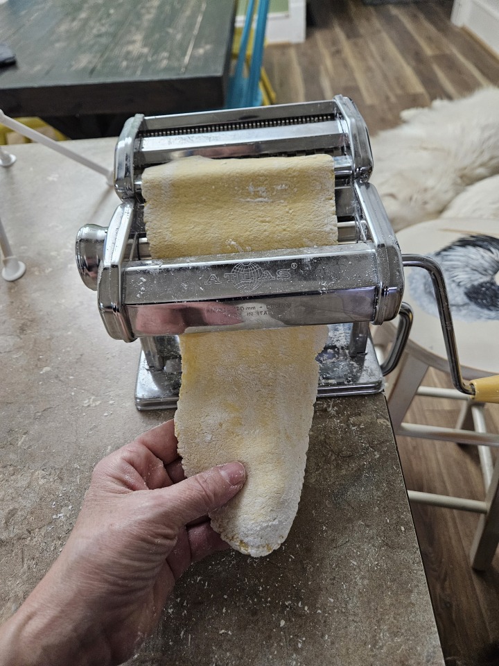 gluten-free pasta being run through a hand cranked pasta machine